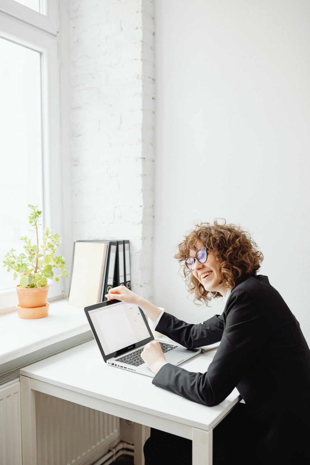 A manager working calmly at her desk by a window.