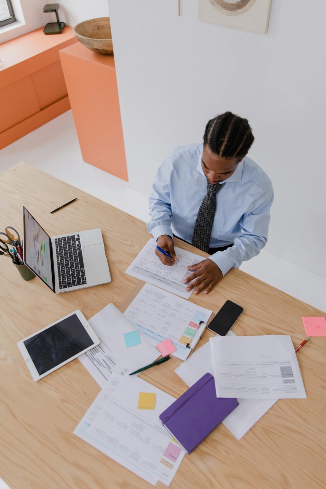 A scheduler at a desk covered in printed rosters, sticky notes and paperwork.